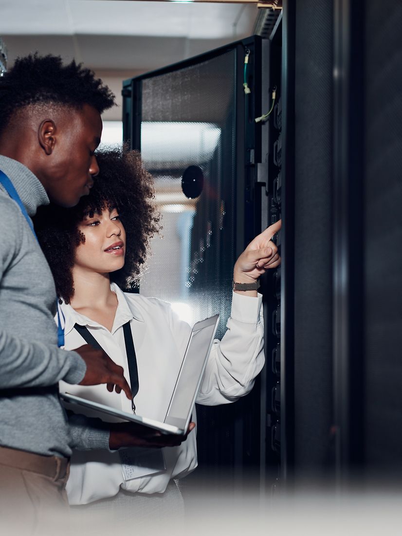 Two people inspect a Telekom server cabinet.
