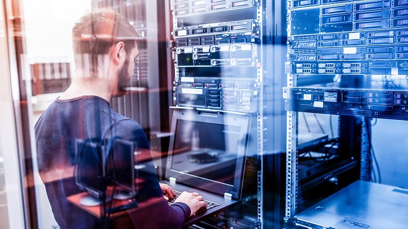A technician works with a laptop in front of a server cabinet for SAP® on Microsoft Azure.