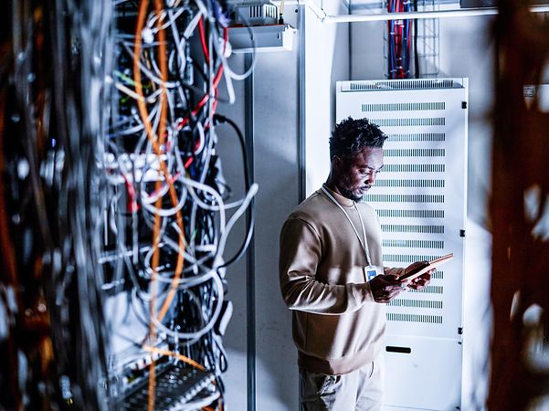 A technician stands in front of a Telekom server cabinet.
