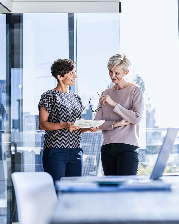 Two women in front of an office window evaluate cloud providers for user-friendliness.