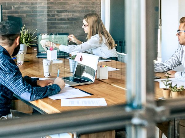 Several colleagues are sitting at a large conference table discussing the MagentaBusiness Cloud.