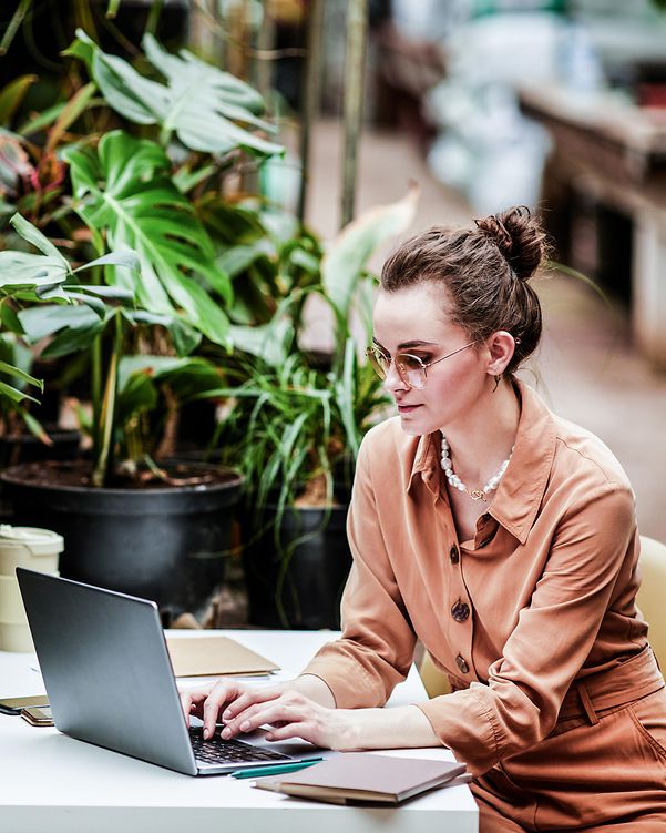 Young designer at a small company, working on her laptop in a café and learning about cloud infrastructure.