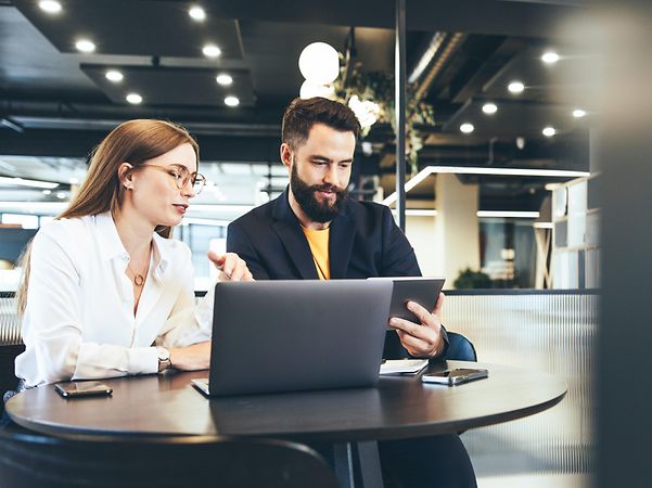 Two people working remotely in a public place with Managed Workplace