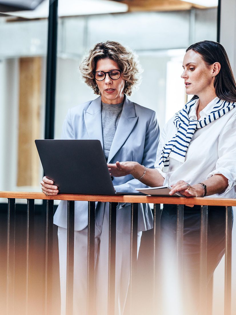 Two women talking at a laptop at a mobile workstation outside the office