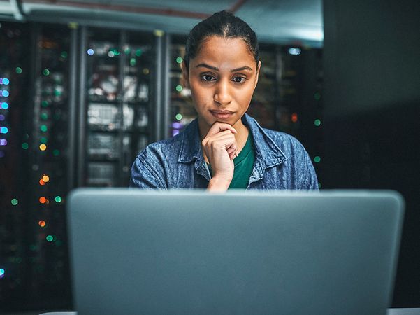 Photograph of an IT technician in a server room with a laptop