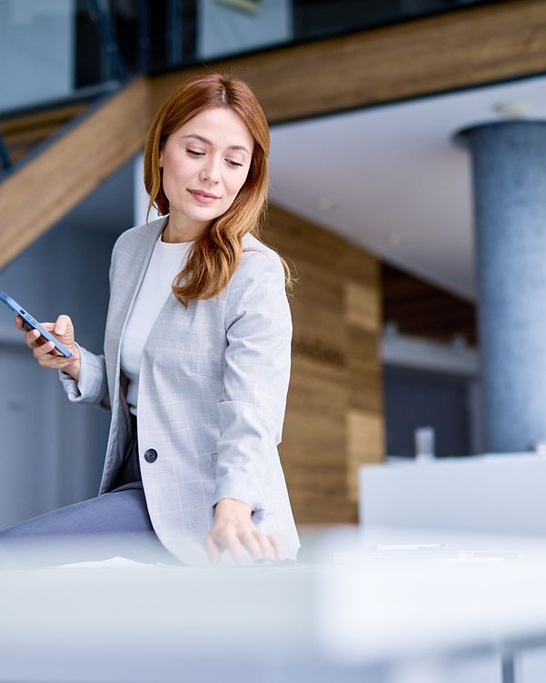 Businesswoman using a smartphone and working in a modern office.
