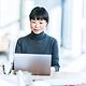 Smiling Japanese businesswoman working on her laptop in the office.
