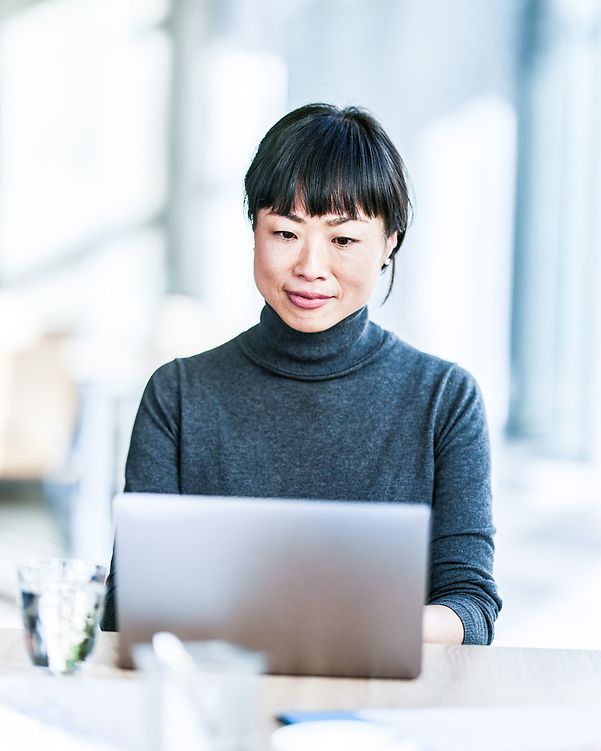 Smiling Japanese businesswoman working on her laptop in the office.