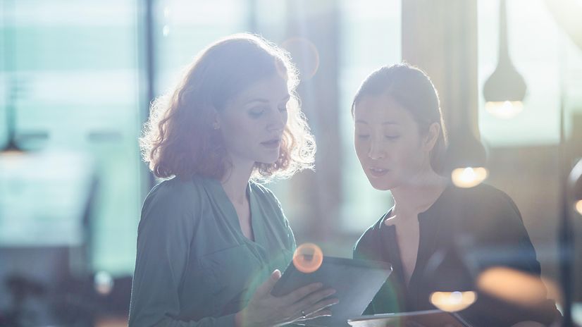 A woman shows another woman the MDM device registration for Samsung and Google on her tablet.