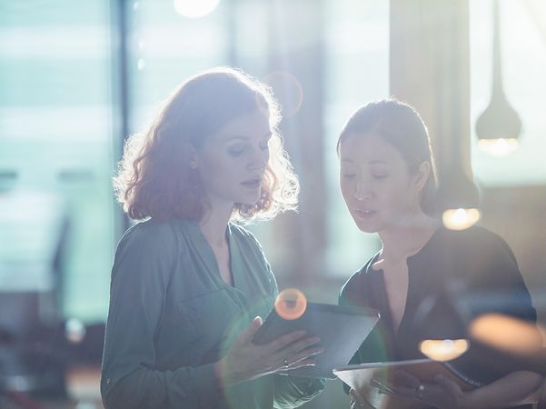 A woman shows another woman the MDM device registration for Samsung and Google on her tablet.