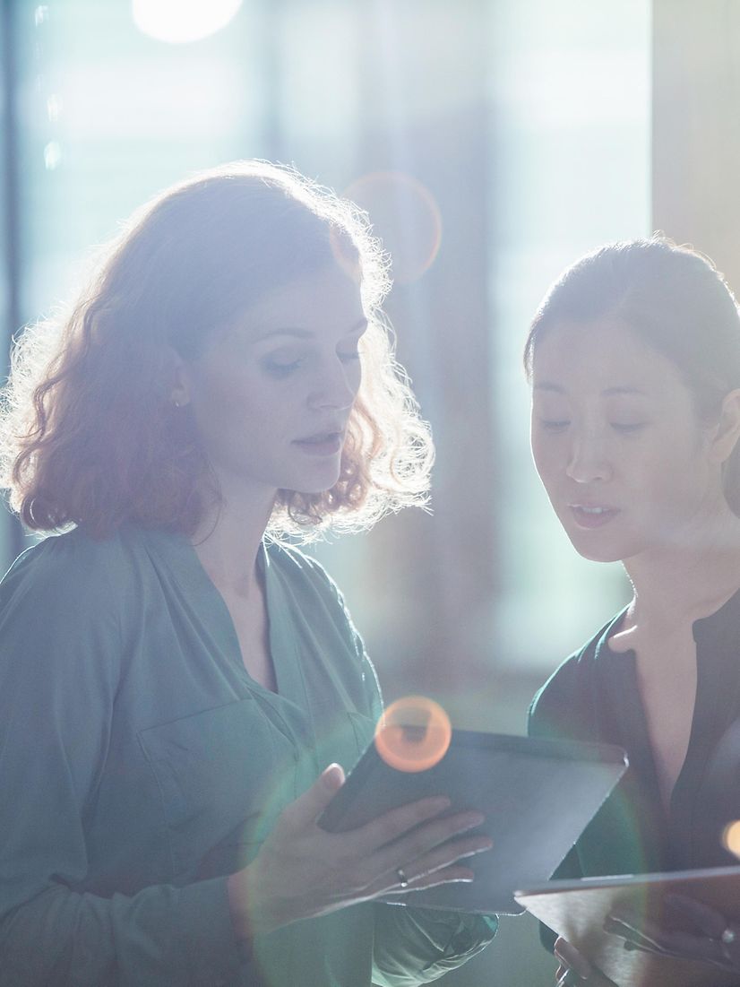 A woman shows another woman the MDM device registration for Samsung and Google on her tablet.
