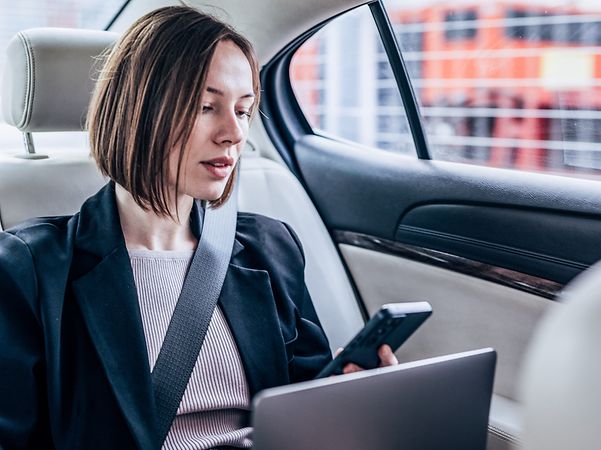 Woman in car searches her contacts for a business contact to call.
