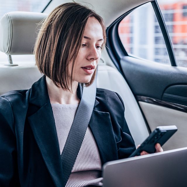 Woman in car searches her contacts for a business contact to call.