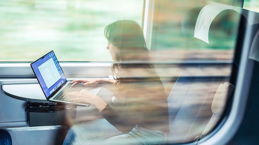 On the train, a woman works intently on her laptop – despite fluctuating network connectivity, everything remains stable.