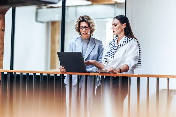 Two women discuss content on a laptop, supported by a stable connection thanks to Mobile Optimisation Pro.