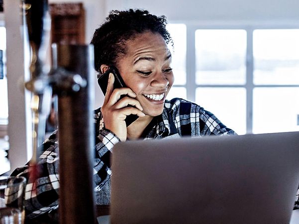 Smiling woman talking on a smartphone while looking at a screen and checking her root certificate.