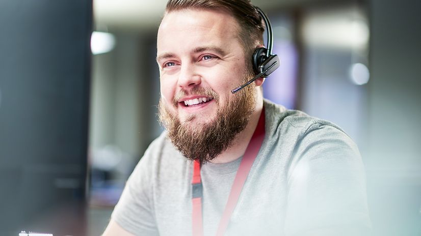 A man from customer service smiles and talks on the phone with a customer.