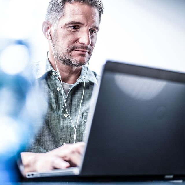 Man with wired headphones working on a laptop with BusinessMail X.400.