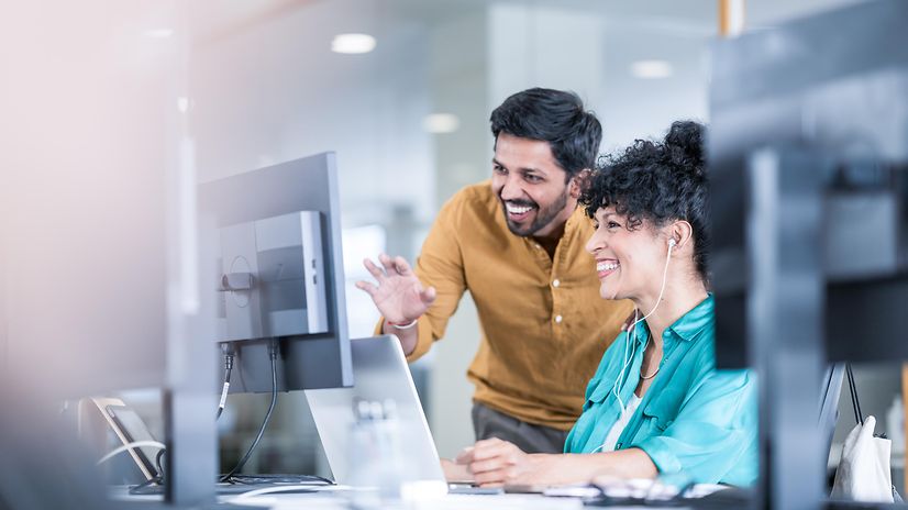 A woman and a man look together at a screen showing Telekom solutions for mobile communication with customers.