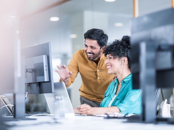A woman and a man look together at a screen showing Telekom solutions for mobile communication with customers.