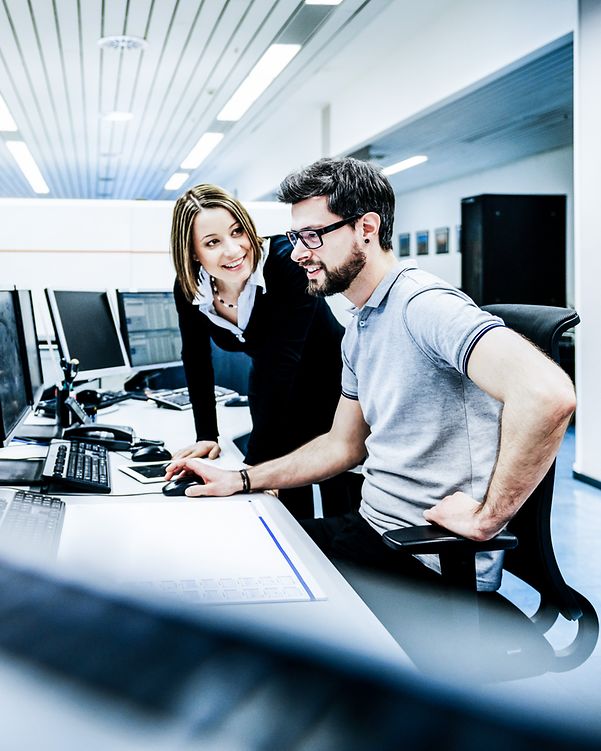 A woman explains something to a man at work.