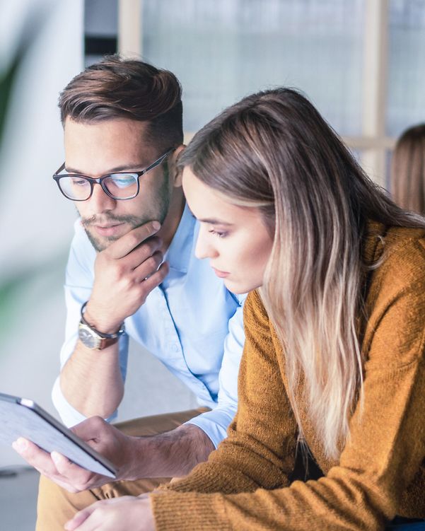 A woman and a man are looking at a tablet.