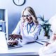 A doctor works behind her desk in her practice and advises a patient.