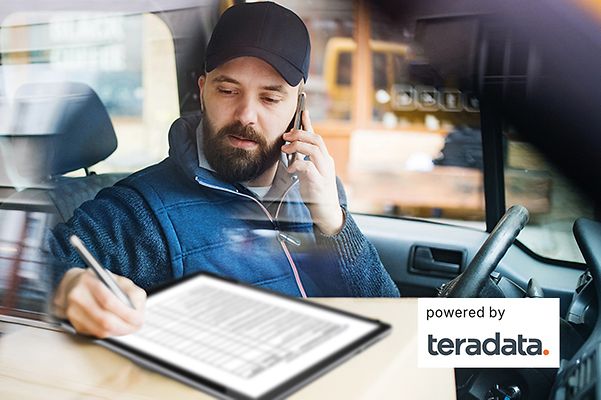 Truck driver sits in his cab and works with Teradata's route optimisation system.