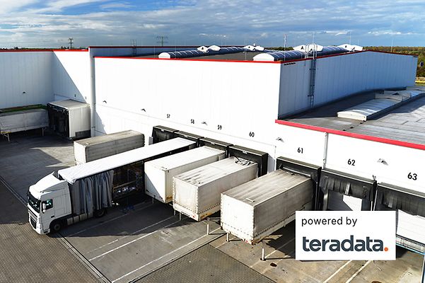 Several lorries are parked in front of warehouses, and the TeraData solution ensures that there are no empty runs.