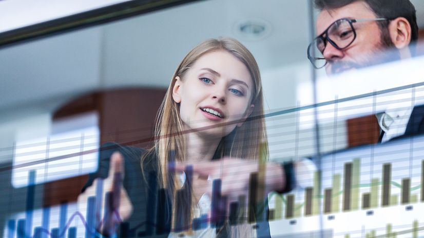Business Analytics Two businesspeople analyse data in front of a futuristic display.
