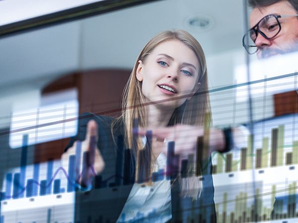 Business Analytics Two businesspeople analyse data in front of a futuristic display.