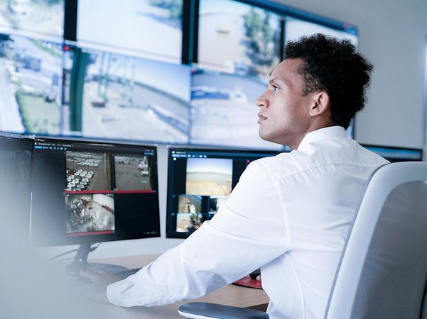 A man is sitting at a desk with several screens in front of him.