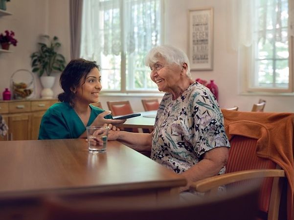 Caregiver simultaneously translates for an elderly woman using her smartphone.