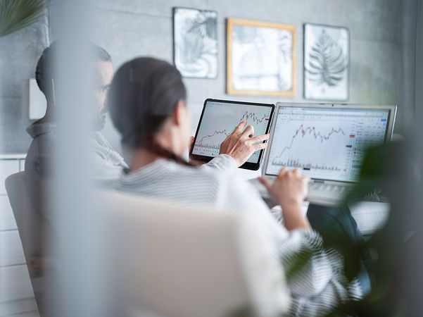 Two people invest in shares and look at share prices on the screen.