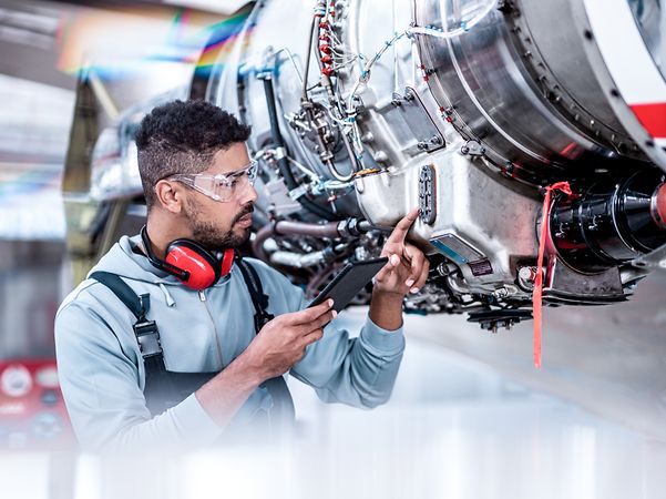 Aircraft maintenance mechanic checking data in front of the jet engine