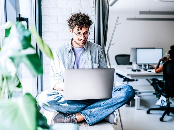 A young man dressed casually, working on his laptop in the office