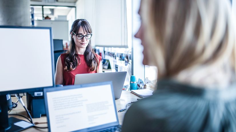 Two women are working together digitally in an office.