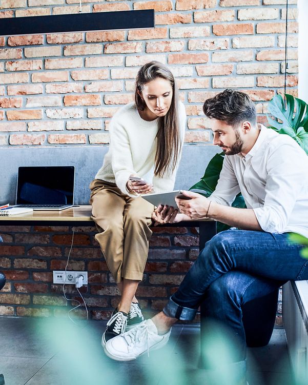 Businessman and businesswoman comparing phones on a telephone and a tablet during a meeting in an office