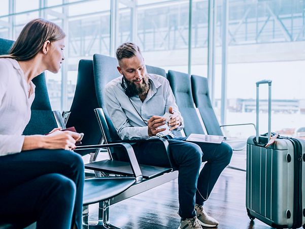 Two people are sitting at the airport and chatting.