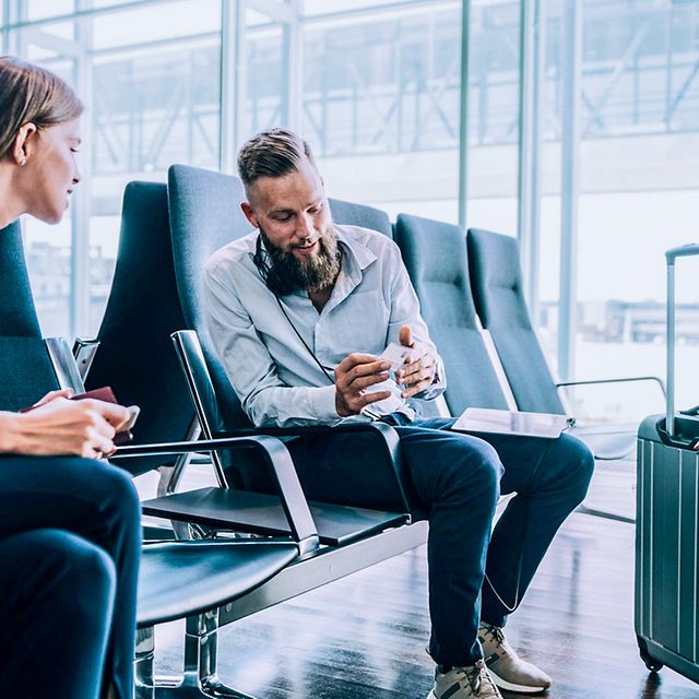 Two people are sitting at the airport and chatting.