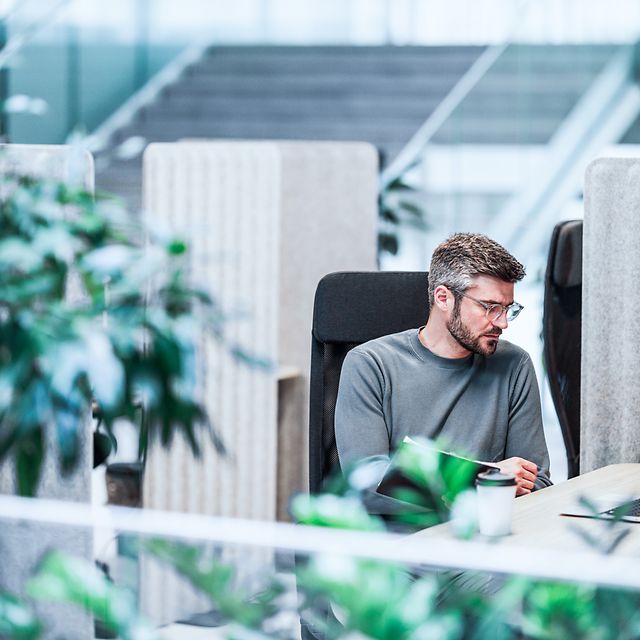 Mann sitzt in einer mobilen Arbeitsumgebung und arbeitet mit einem Laptop.