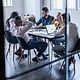 A team sits at a conference table with a MacBook on it.