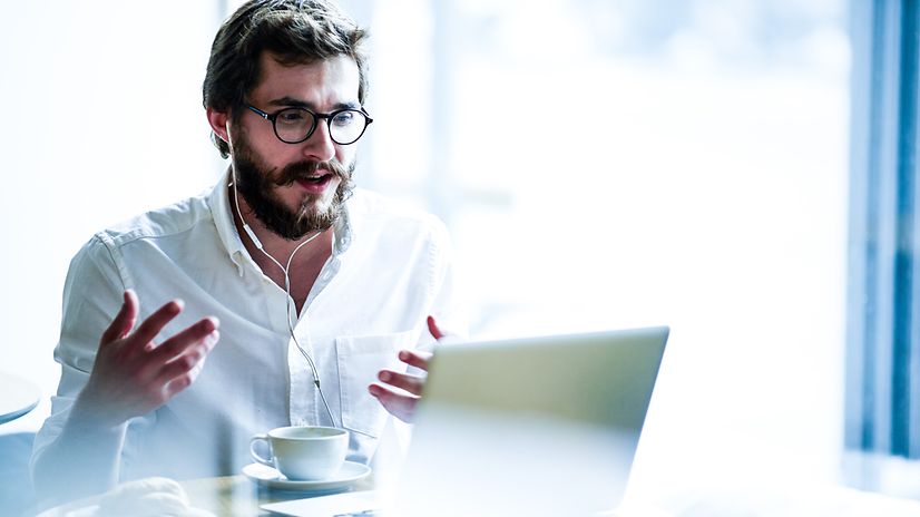 Man participating in a video call, wearing Apple Airpods and sitting in front of a MacBook