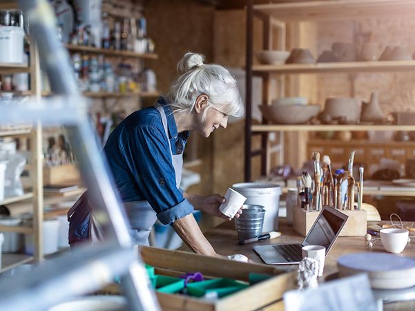 A craftswoman looks at her workshop's website on her laptop and is delighted with her e-commerce successes.
