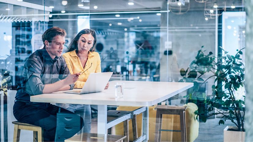 A woman and a man are sitting together and looking at a laptop.