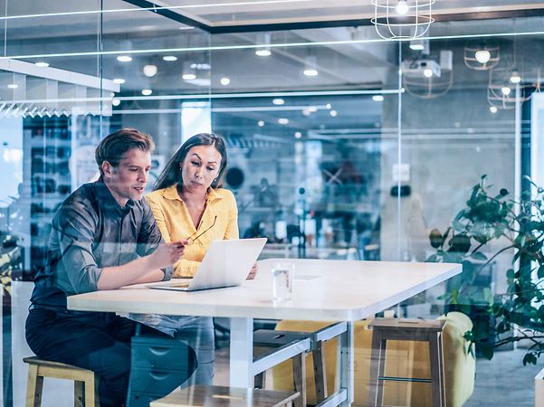 A woman and a man are sitting together and looking at a laptop.