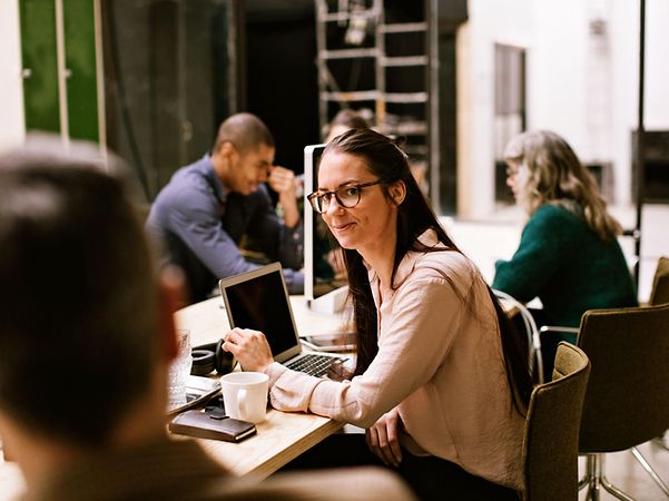 Employees sit around a meeting table and are delighted with CompanyFlex Services.