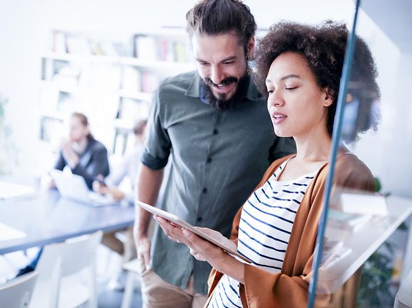 Mitarbeitende im Büro schauen sich auf einem Tablet den Internet und Festnetz Tarife Vergleich an