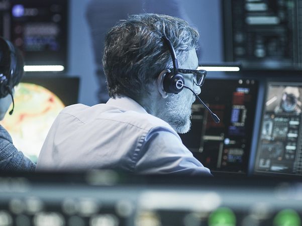 Man sitting in front of computer screens wearing headphones