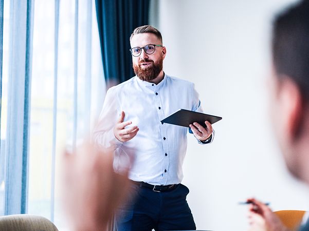 Mann steht mit Tablet vor Publikum